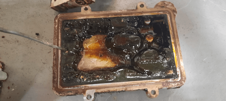 The base of a hot melt tank which is covered in gelled up glue. 